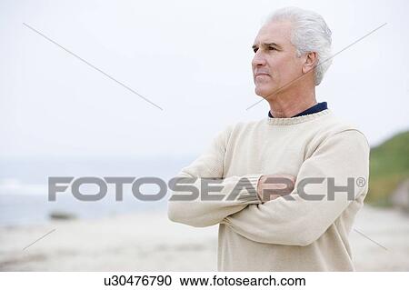 Stock Image - Man at the beach with arms crossed. Fotosearch
