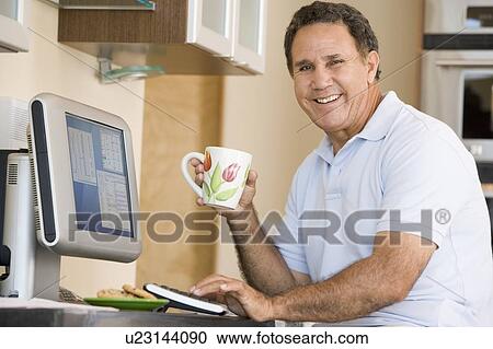 Man in kitchen with computer and coffee smiling View Large Photo Image Stock Image - Man in kitchen with computer and coffee smiling. Fotosearch