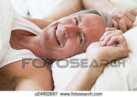 Stock Photo - Man lying in bed smiling. Fotosearch