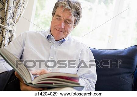 Stock Photo - Man relaxing with book in living room. Fotosearch