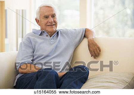 Man sitting in living room smiling View Large Photo Image Stock Photography - Man sitting in living room smiling. Fotosearch