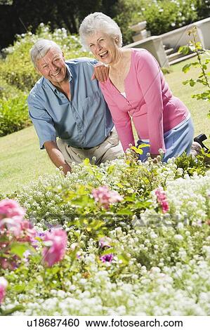 Stock Image - Senior couple in a flower garden. Fotosearch