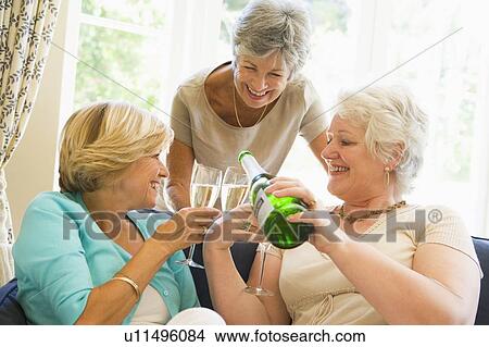 Three women in living room drinking champagne and smiling View Large Photo Image Picture - Three women in living room drinking champagne and smiling. Fotosearch