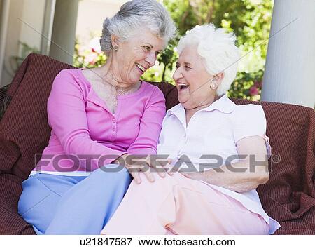 Two senior women sitting outdoors on a chair View Large Photo Image Stock Photo - Two senior women sitting outdoors on a chair. Fotosearch