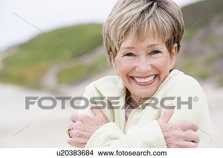 Woman at the beach cold and smiling View Large Photo Image Picture - Woman at the beach cold and smiling. Fotosearch