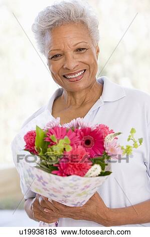 Woman holding flowers and smiling View Large Photo Image Stock Image - Woman holding flowers and smiling. Fotosearch