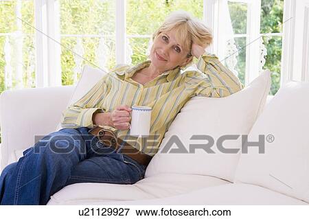 Woman in living room with coffee smiling View Large Photo Image Stock Photo - Woman in living room with coffee smiling. Fotosearch