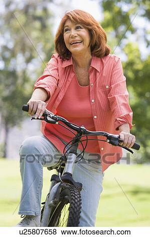 Woman on bike outdoors smiling View Large Photo Image Stock Photo - Woman on bike outdoors smiling. Fotosearch