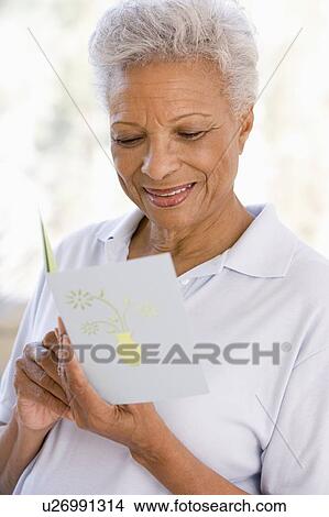 Picture - Woman reading card and smiling. Fotosearch