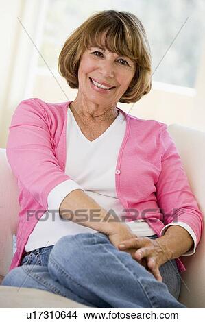 Woman sitting in living room smiling View Large Photo Image Picture - Woman sitting in living room smiling. Fotosearch