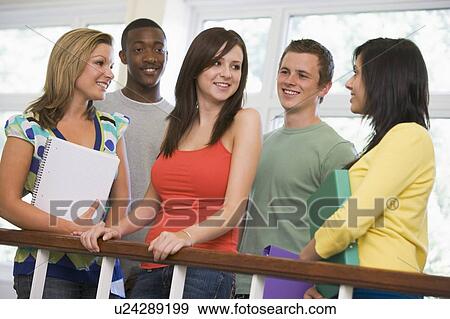 Stock Photo - Five students in corridor leaning on railing with notebooks. Fotosearch