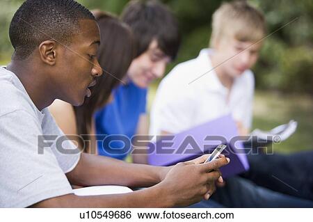 Four students outdoors studying with one checking cellular phone (depth of field) View Large Photo Image Stock Photograph - Four students outdoors studying with one checking cellular phone (depth of field). Fotosearch