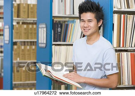 Man in library holding book (depth of field) View Large Photo Image Stock Image - Man in library holding book (depth of field). Fotosearch