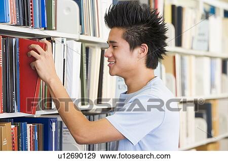 Stock Photo - Man in library pulling book off a shelf (depth of field). Fotosearch