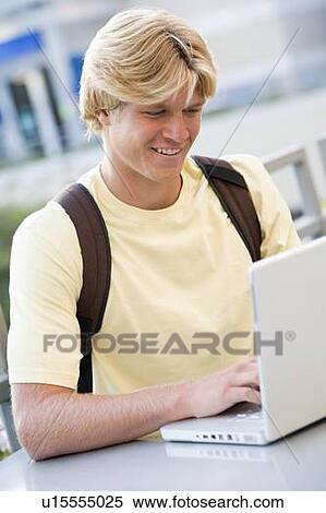 Man sitting at table outdoors with laptop smiling (selective focus) View Large Photo Image Stock Photography - Man sitting at table outdoors with laptop smiling (selective focus). Fotosearch