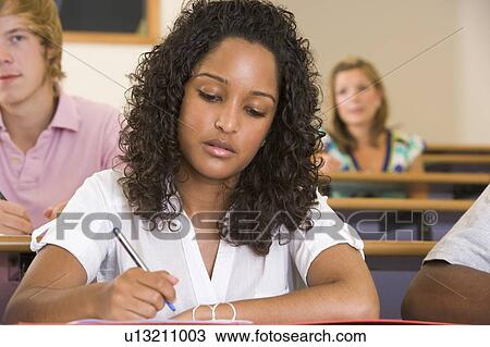 Stock Image - Student in class taking notes (selective focus). Fotosearch