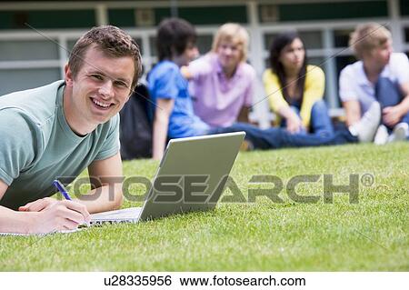 Student outdoors on lawn using laptop with other students in background (selective focus) View Large Photo Image Stock Photograph - Student outdoors on lawn using laptop with other students in background (selective focus). Fotosearch