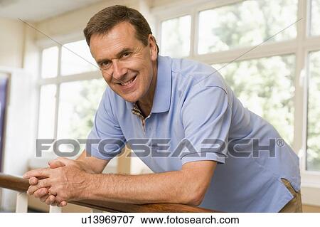 Stock Photo - Teacher in corridor leaning on railing. Fotosearch