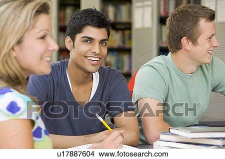 Picture - Three people in library studying (selective focus). Fotosearch