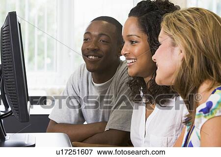 Stock Photo - Three people sitting at a computer terminal (high key). Fotosearch