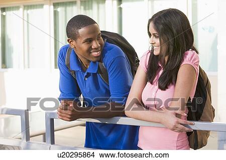 Two people standing on balcony leaning on railing View Large Photo Image Picture - Two people standing on balcony leaning on railing. Fotosearch