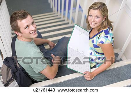 Stock Image - Two students sitting on staircase with notebooks (selective focus). Fotosearch