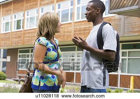 Two students standing outdoors talking View Large Photo Image Stock Photo - Two students standing outdoors talking. Fotosearch