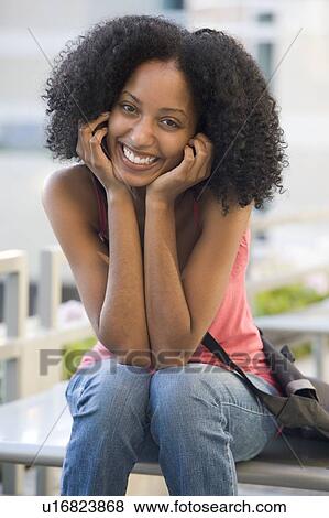 Woman sitting on bench outdoors smiling (selective focus) View Large Photo Image Stock Photo - Woman sitting on bench outdoors smiling (selective focus). Fotosearch