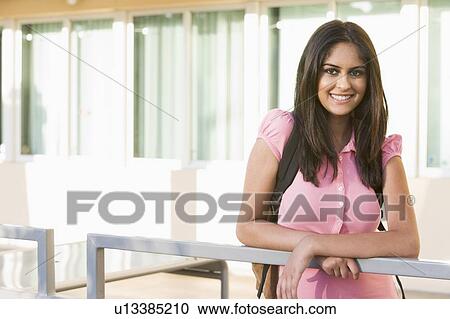 Stock Image - Woman standing on balcony leaning on railing. Fotosearch