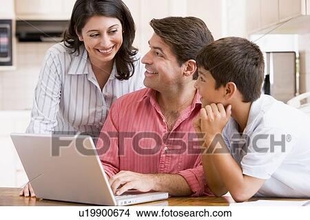 Family in kitchen with laptop smiling View Large Photo Image Picture - Family in kitchen with laptop smiling. Fotosearch