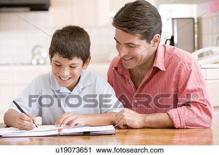 Man helping young boy in kitchen doing homework and smiling View Large Photo Image Stock Image - Man helping young boy in kitchen doing homework and smiling. Fotosearch