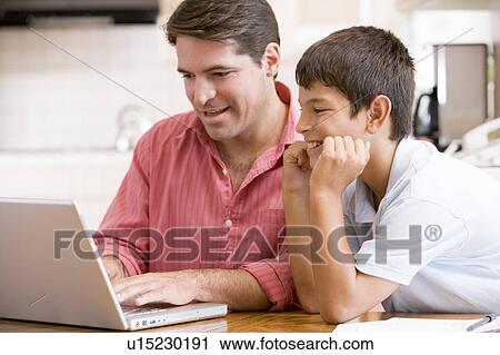Man helping young boy in kitchen with laptop smiling View Large Photo Image Stock Image - Man helping young boy in kitchen with laptop smiling. Fotosearch