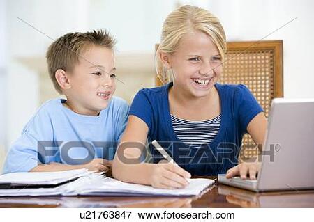 Two young children with laptop doing homework in dining room smiling View Large Photo Image Stock Photo - Two young children with laptop doing homework in dining room smiling. Fotosearch