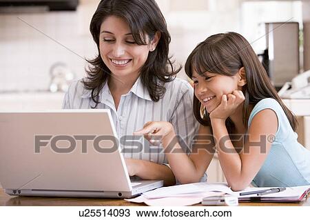 Woman and young girl in kitchen with laptop and paperwork smiling View Large Photo Image Stock Image - Woman and young girl in kitchen with laptop and paperwork smiling. Fotosearch