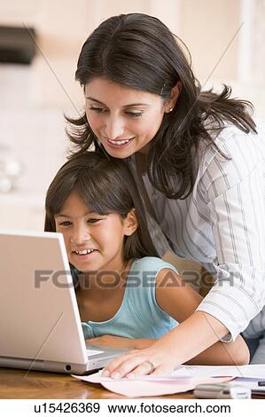 Woman and young girl in kitchen with laptop and paperwork smiling View Large Photo Image Stock Photo - Woman and young girl in kitchen with laptop and paperwork smiling. Fotosearch