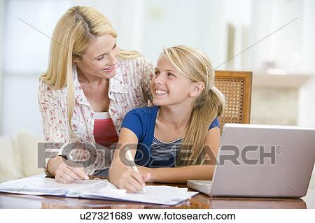 Woman helping young girl with laptop do homework in dining room View Large Photo Image Stock Photo - Woman helping young girl with laptop do homework in dining room. Fotosearch
