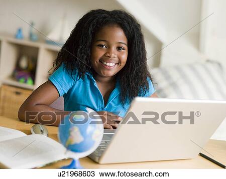 Stock Image - Young Girl Doing Her Homework On A Laptop. Fotosearch