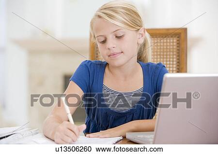 Stock Image - Young Girl Doing Homework And Using Laptop. Fotosearch