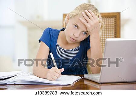Young girl with laptop doing homework in dining room looking unhappy View Large Photo Image Stock Image - Young girl with laptop doing homework in dining room looking unhappy. Fotosearch