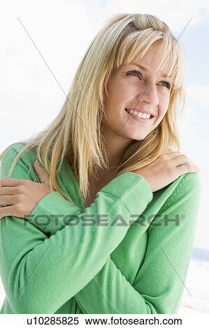 Stock Photography - Blonde woman in a green sweater posing outdoors. Fotosearch