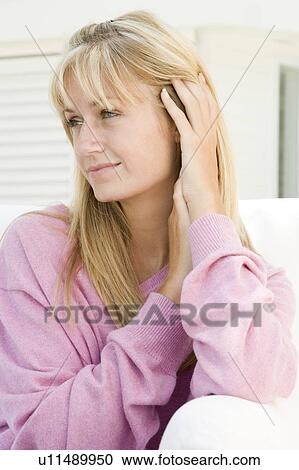 Stock Image - Blonde woman in a pink sweater posing outdoors. Fotosearch
