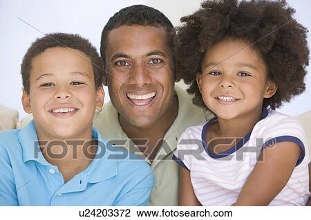 Man and two young children sitting in living room smiling View Large Photo Image Stock Image - Man and two young children sitting in living room smiling. Fotosearch