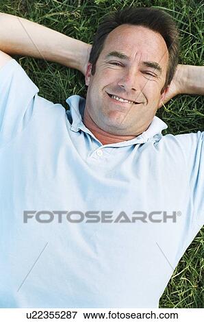 Stock Photo - Man lying outdoors smiling. Fotosearch