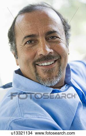 Man sitting indoors smiling (high key) View Large Photo Image Picture - Man sitting indoors smiling (high key). Fotosearch