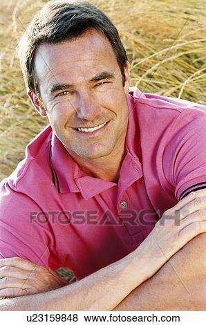 Stock Photo - Man sitting outdoors smiling. Fotosearch