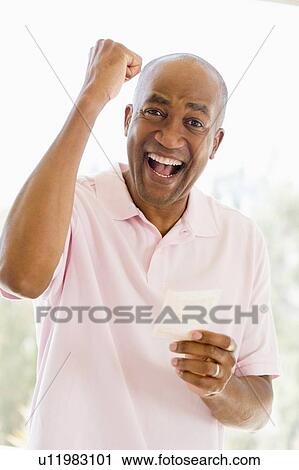 Stock Image - Man with winning lottery ticket excited and smiling. Fotosearch