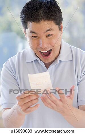 Stock Image - Man with winning lottery ticket excited and smiling. Fotosearch