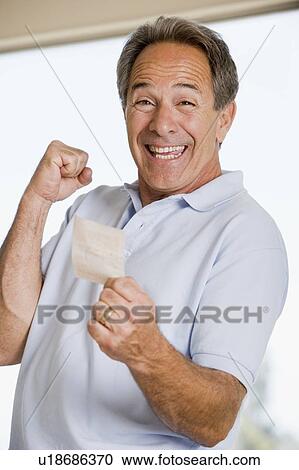 Stock Image - Man with winning lottery ticket excited and smiling. Fotosearch