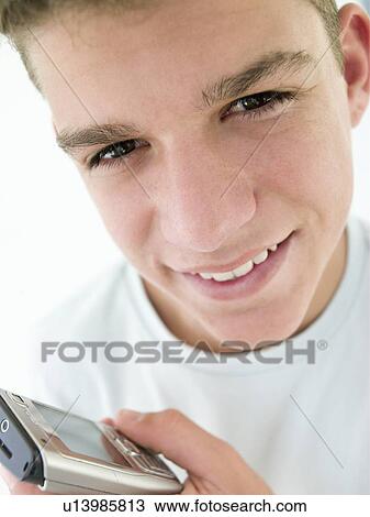 Stock Image - Teenage boy using cellular phone and smiling. Fotosearch