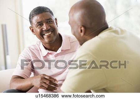Stock Photograph - Two men in living room talking and smiling. Fotosearch
